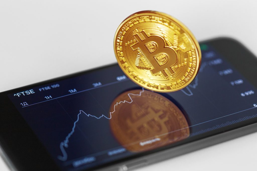 A crypto currency chart appearing on a phone screen with bitcoin on top of the screen