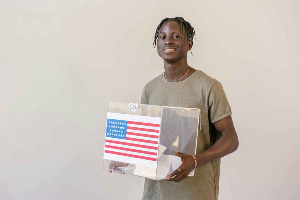 An image of a black guy, carrying a ballot box with the US flag in it