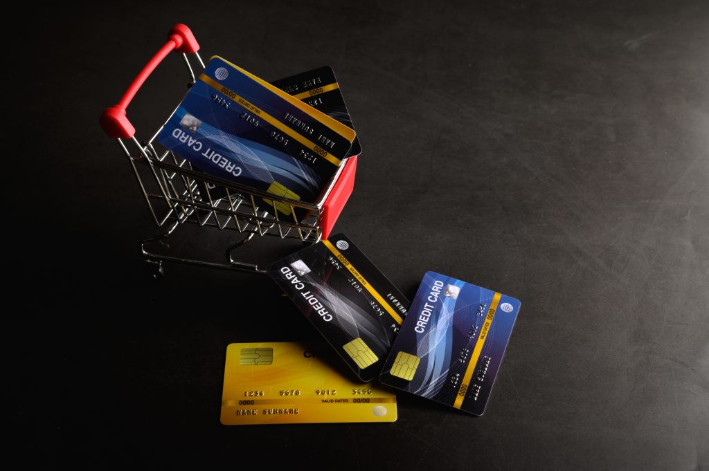 An image of credit cards laying on the floor and one card is placed inside a cart