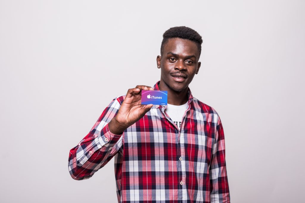 An image of a black guy holding an itunes gift card