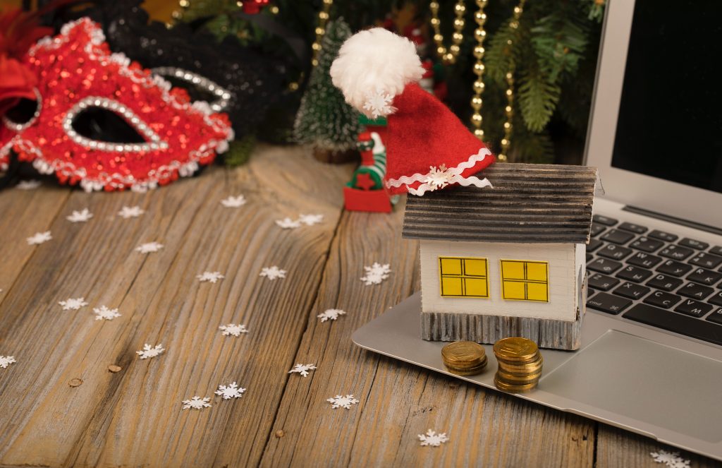 An Image of a small paper house with santa clause hat placed on a laptop