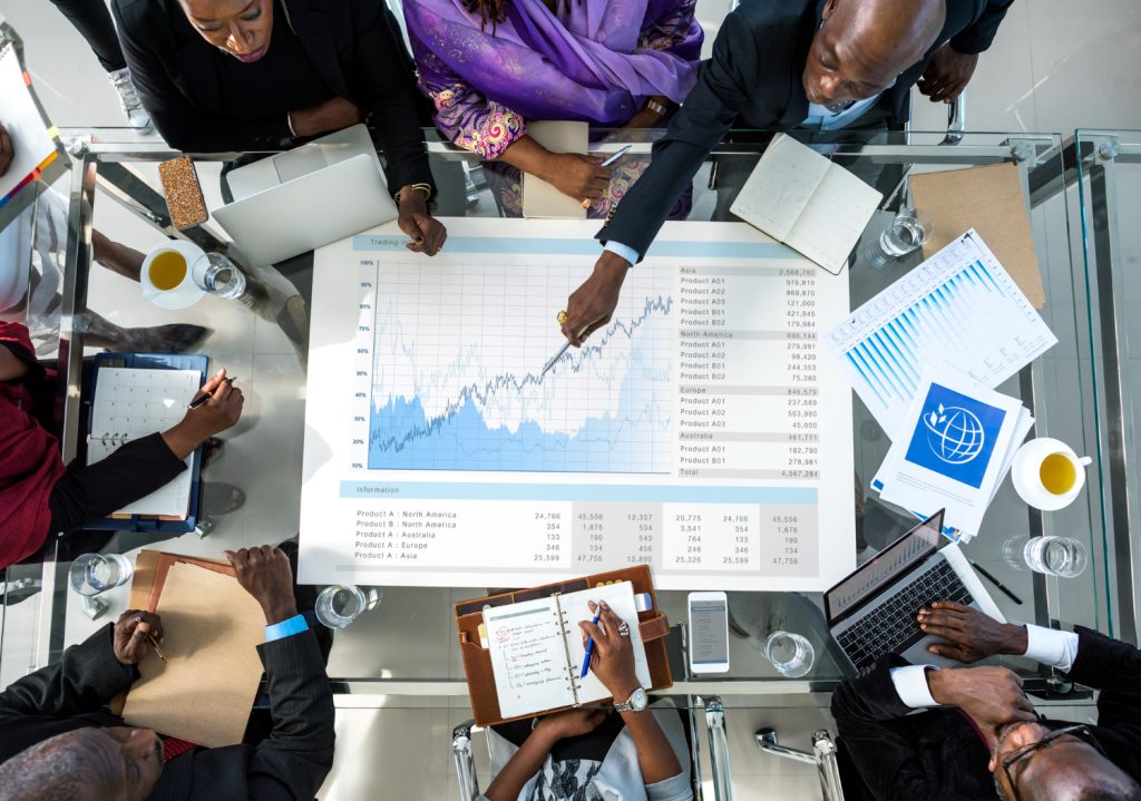 A diverse group of business professionals from different ethnic backgrounds engaging in a meeting, discussing partnership strategies in a modern office setting.