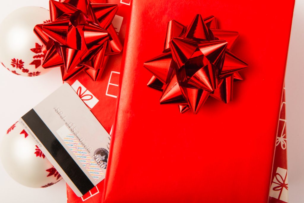 An image of gifts wrapped. in red wrapping paper with a gift card by the side