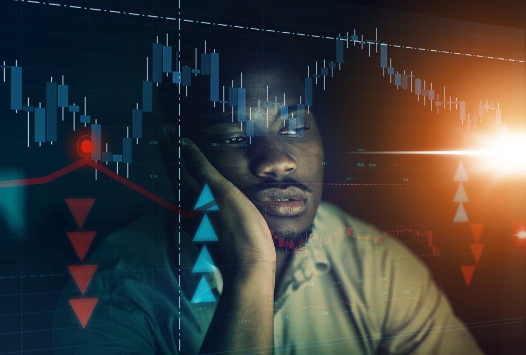 An image of a black guy looking depressed from a failed FOMO trade with the crypto market chart on his face.