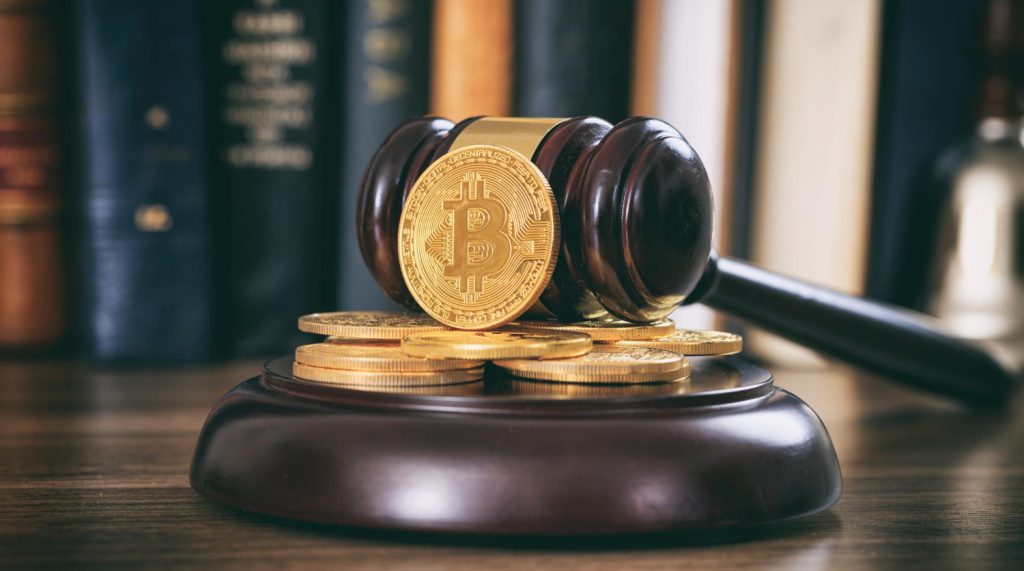 “A judge’s wooden gavel resting beside stacked cryptocurrency coins on a wooden desk, symbolizing legal and regulatory issues around crypto.”